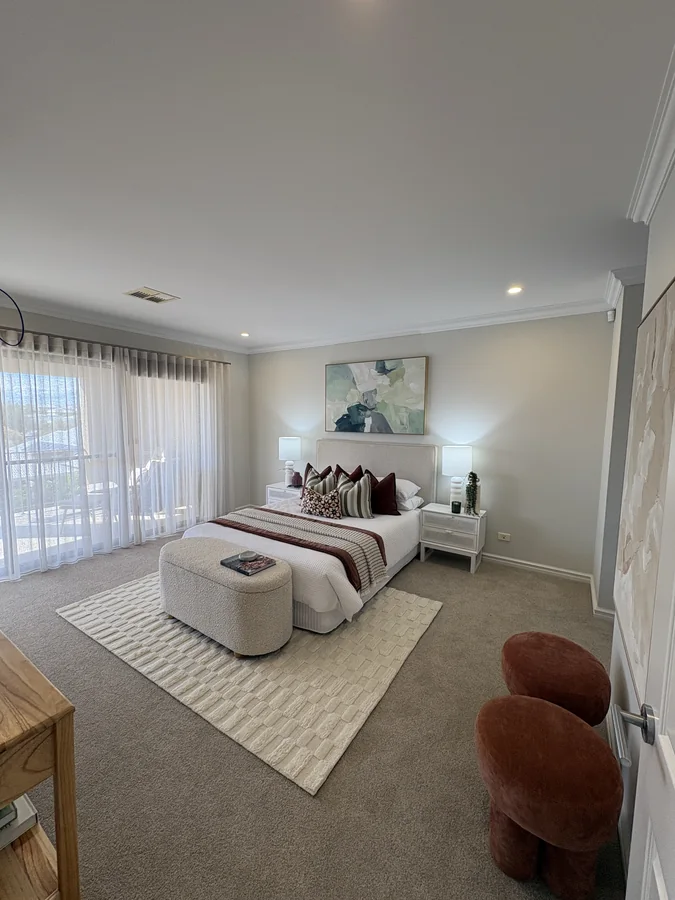 Bedroom with striped cushions, burgundy accents, a cream ottoman and sheer curtains