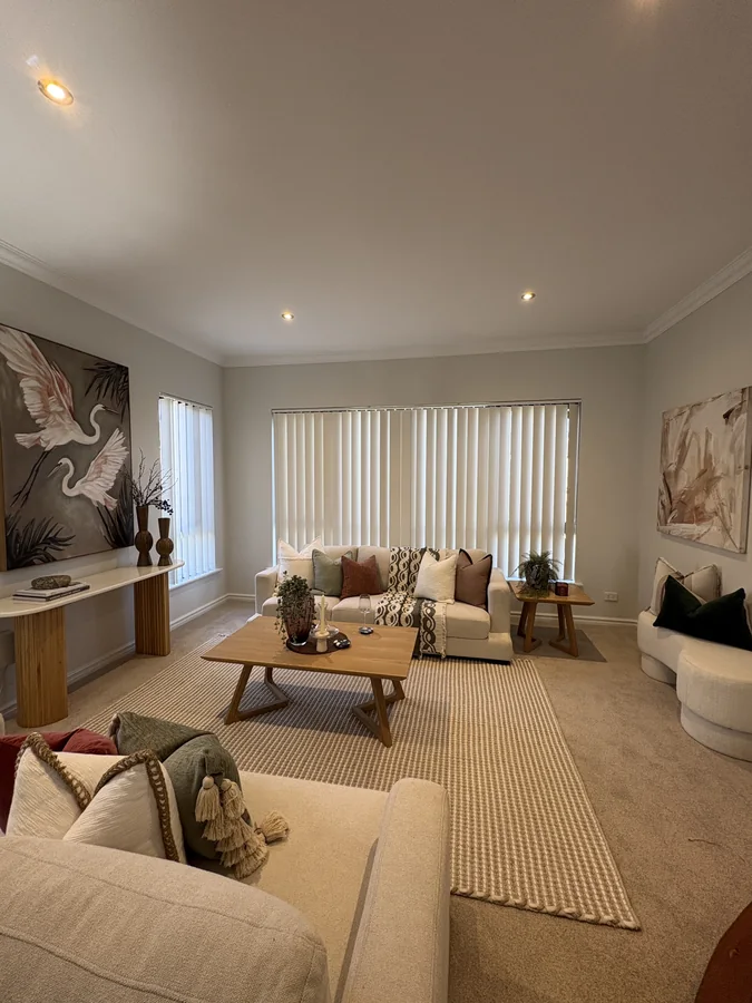 Living room with ivory sofas, patterned cushions, timber tables and bird artwork
