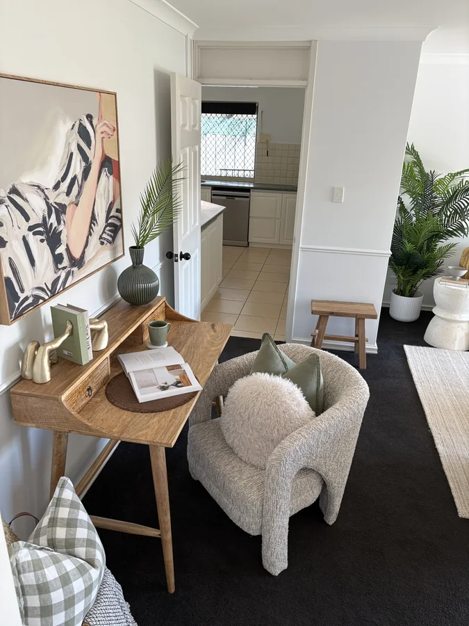 Timber writing desk, textured cream chair and green accents in a styled study nook