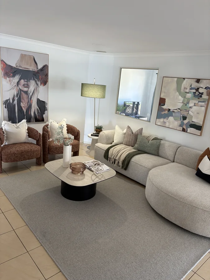 Light living room with a curved sofa, rust armchairs and green accents
